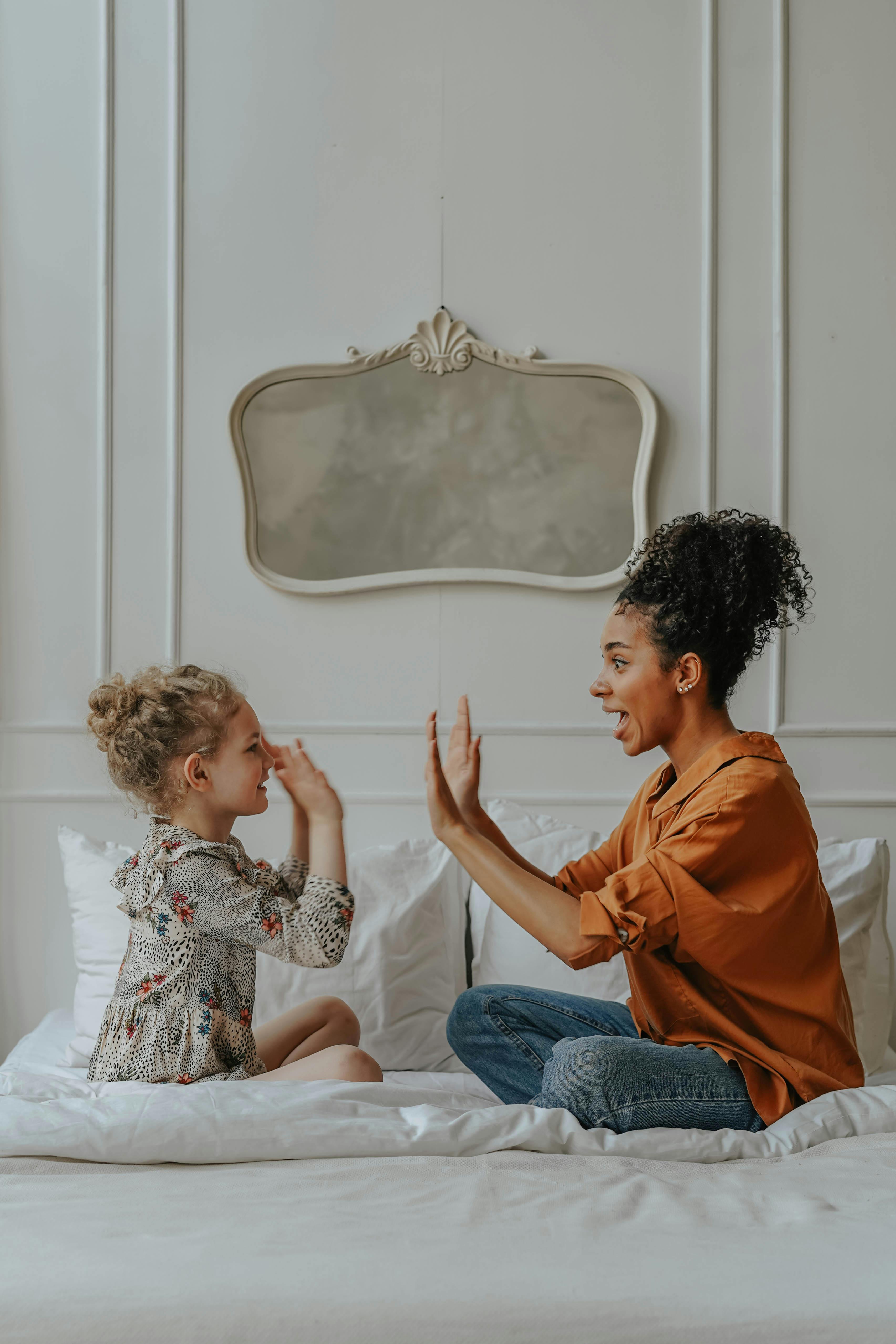 Mother playing with daughter on bed — joyful single motherhood
